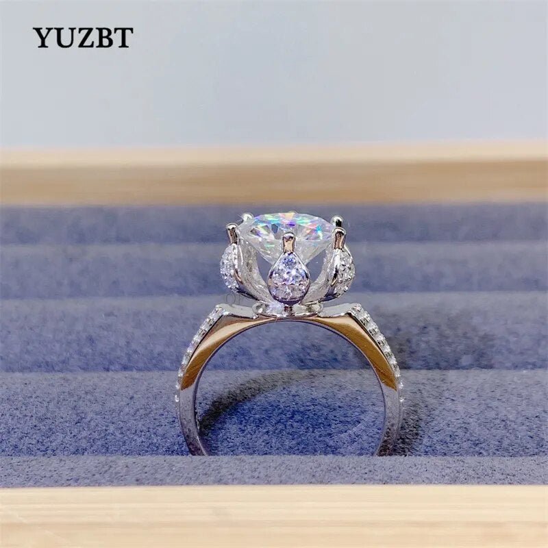 White gold plated ring featuring a 3 carat round cut moissanite gemstone in a floral blossom setting.