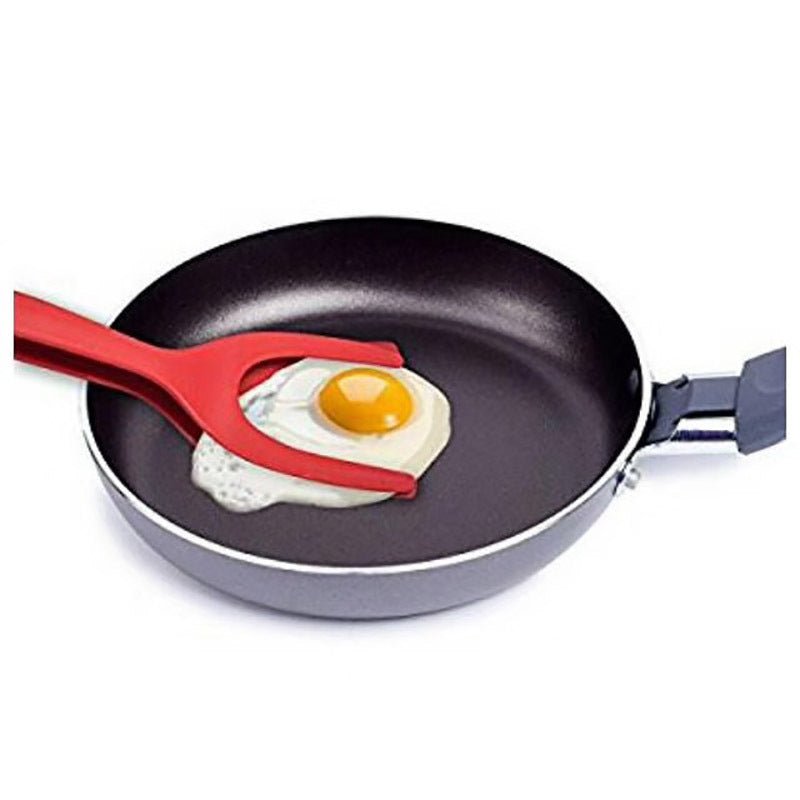 Red 2-in-1 spatula tongs flipping a fried egg in a pan. Kitchen cooking accessory.