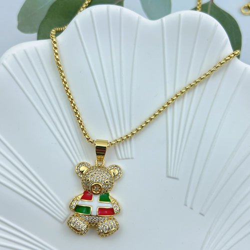 Crystal teddy bear pendant necklace with red, white, and green details on a gold chain.