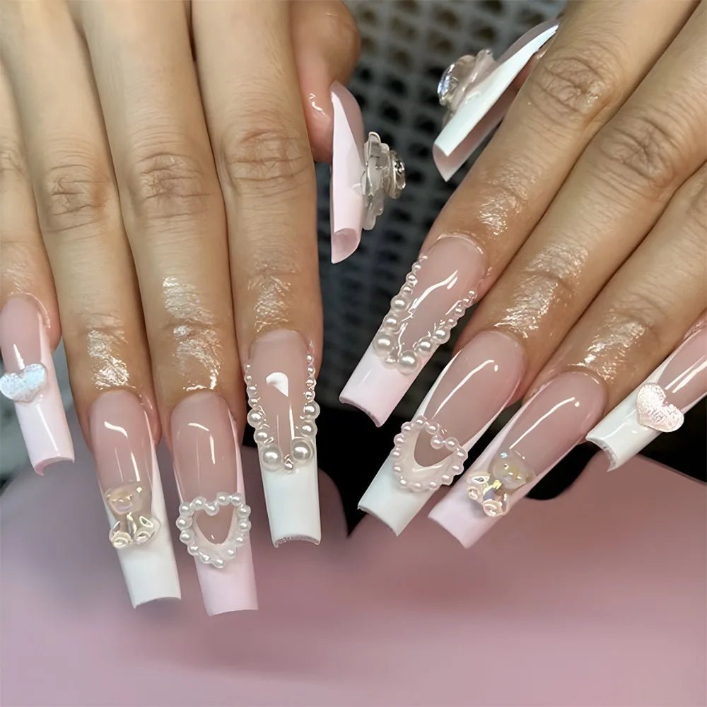 Long coffin nails with French tips, pearl heart and bear charms, and rhinestone accents.
