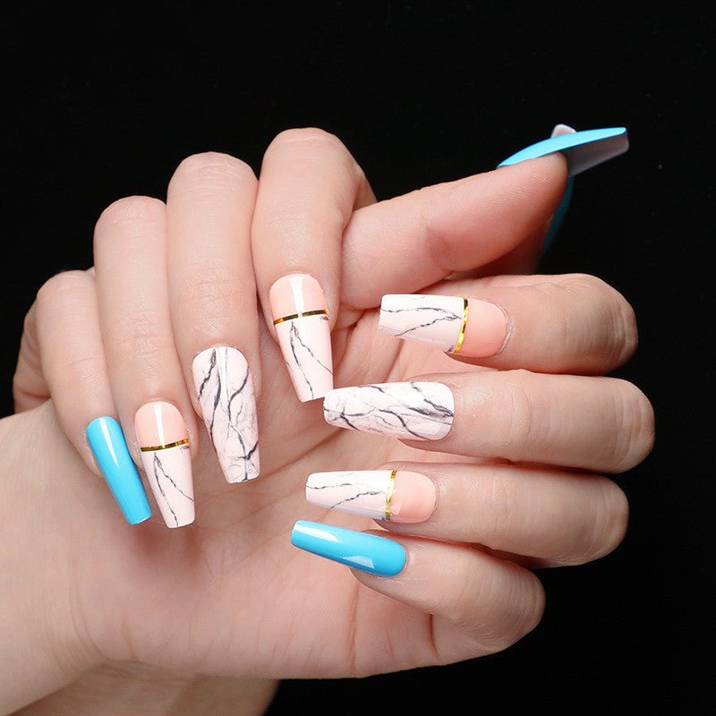 Hand wearing pink and blue coffin-shaped press-on nails with marble and gold stripe accents.