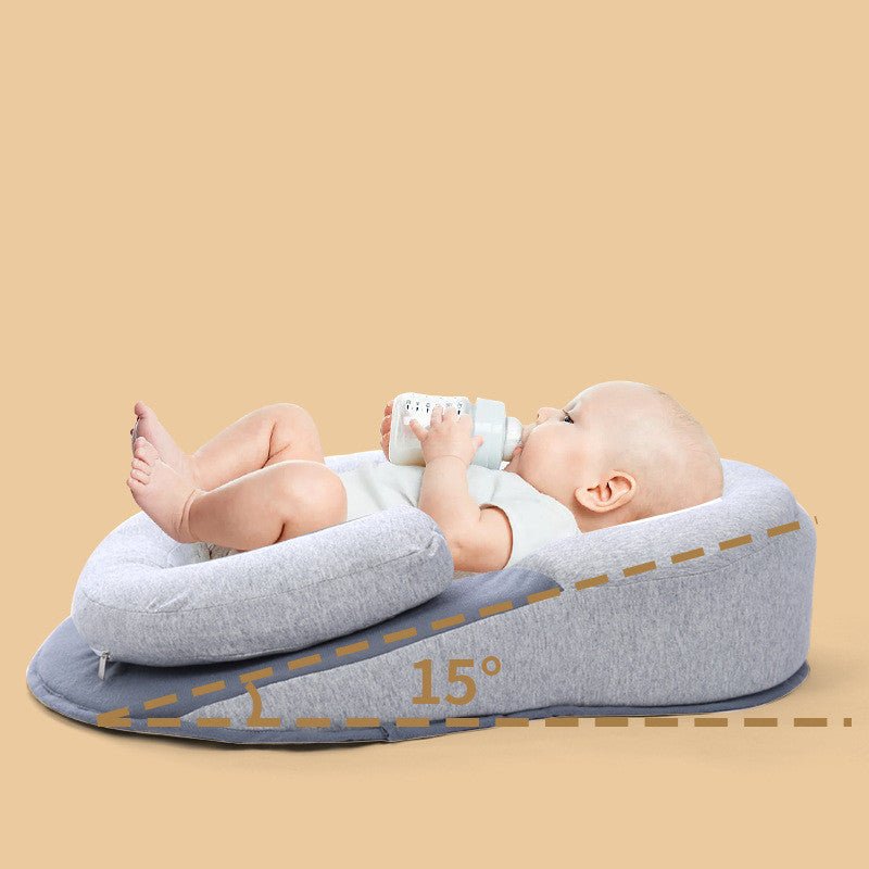 Baby in gray 15-degree incline pillow feeding from a bottle. Infant head support.