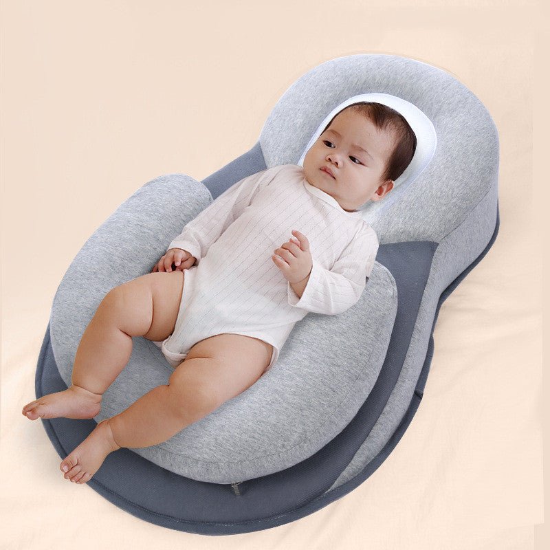 Baby lying in a gray infant sleep pod with head support pillow.