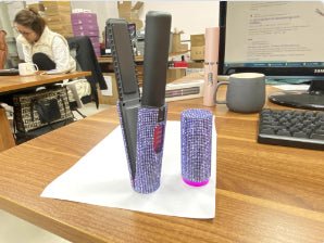 Rhinestone-covered cordless hair straightener and matching case on a desk.
