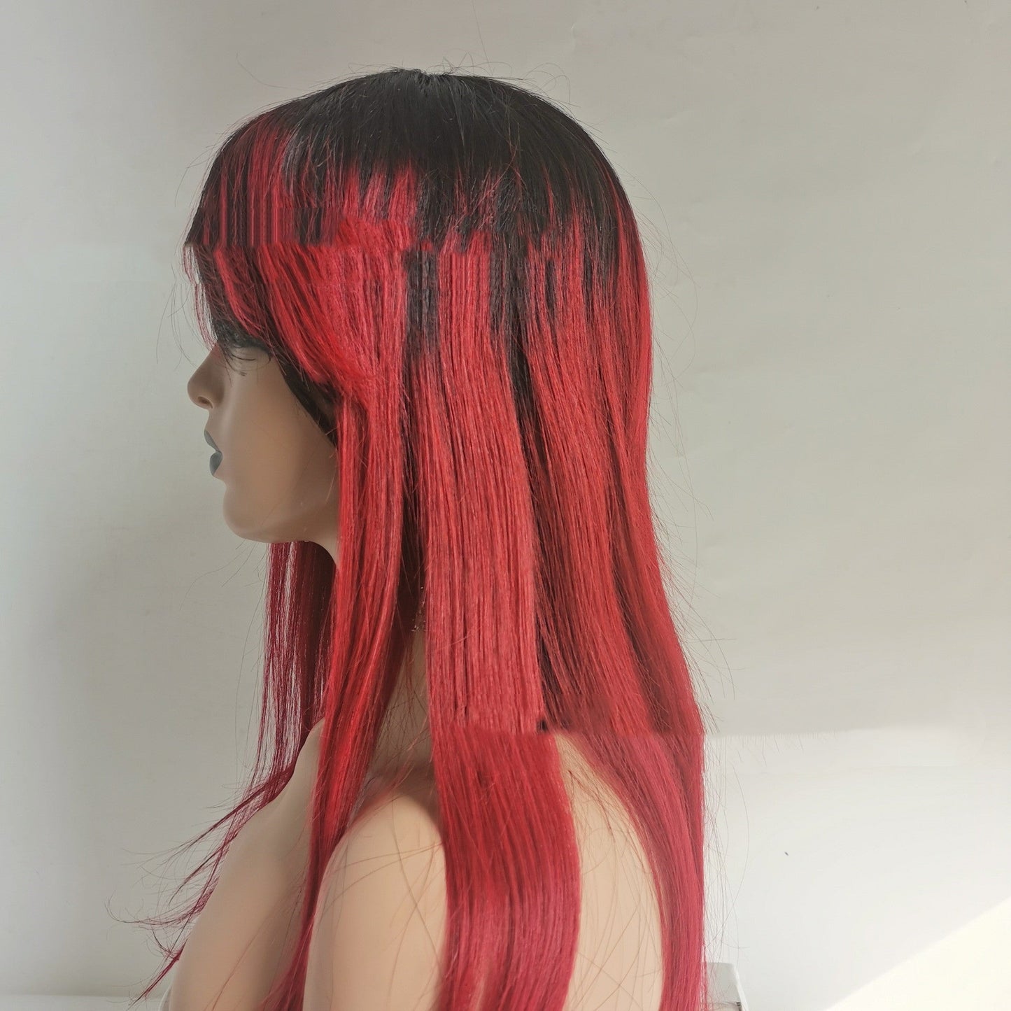 Red and black human hair wig with bangs, side view.