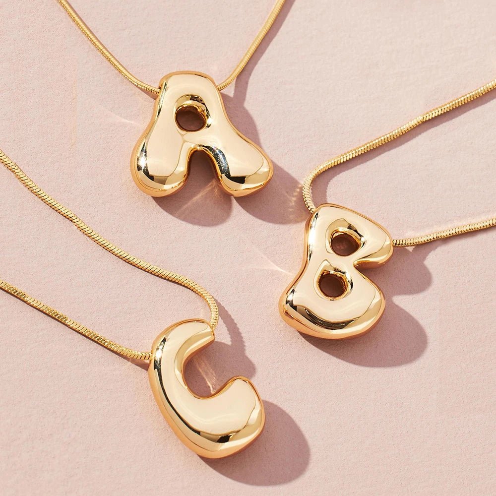 Gold initial necklaces: Letter A, B, and C pendants on snake chains.