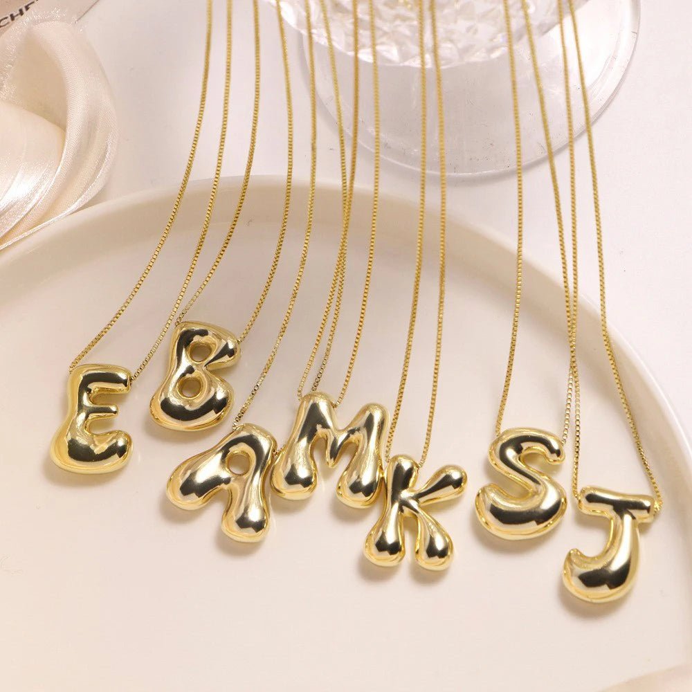 Gold initial pendant necklaces on display. Each has a different letter.
