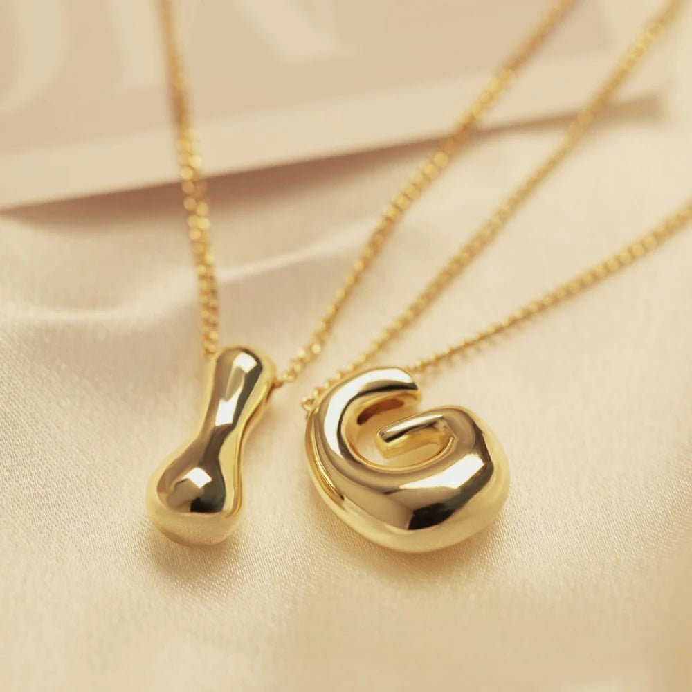 Two gold initial necklaces: a plain pendant and one shaped like the letter 'G'.