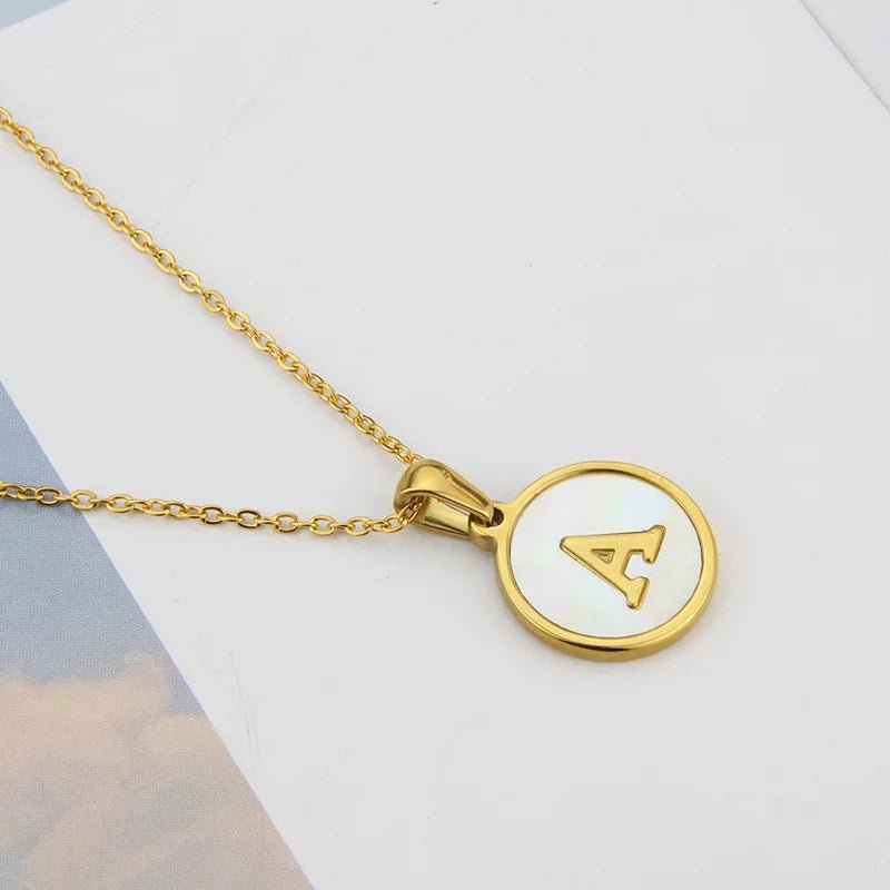 Gold initial necklace with mother of pearl pendant featuring the letter A.