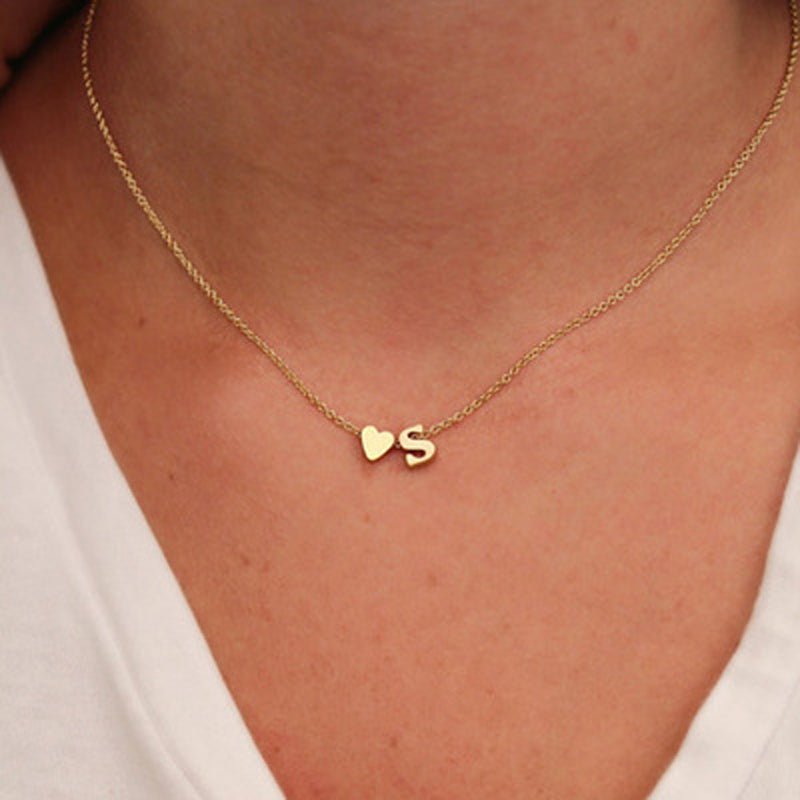 Gold initial necklace with heart and letter S charm.